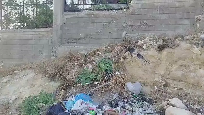 Ermenek Devlet Hastanesi bahçesinin duvar dibine atılmış plastik şişe ve çöp yığını