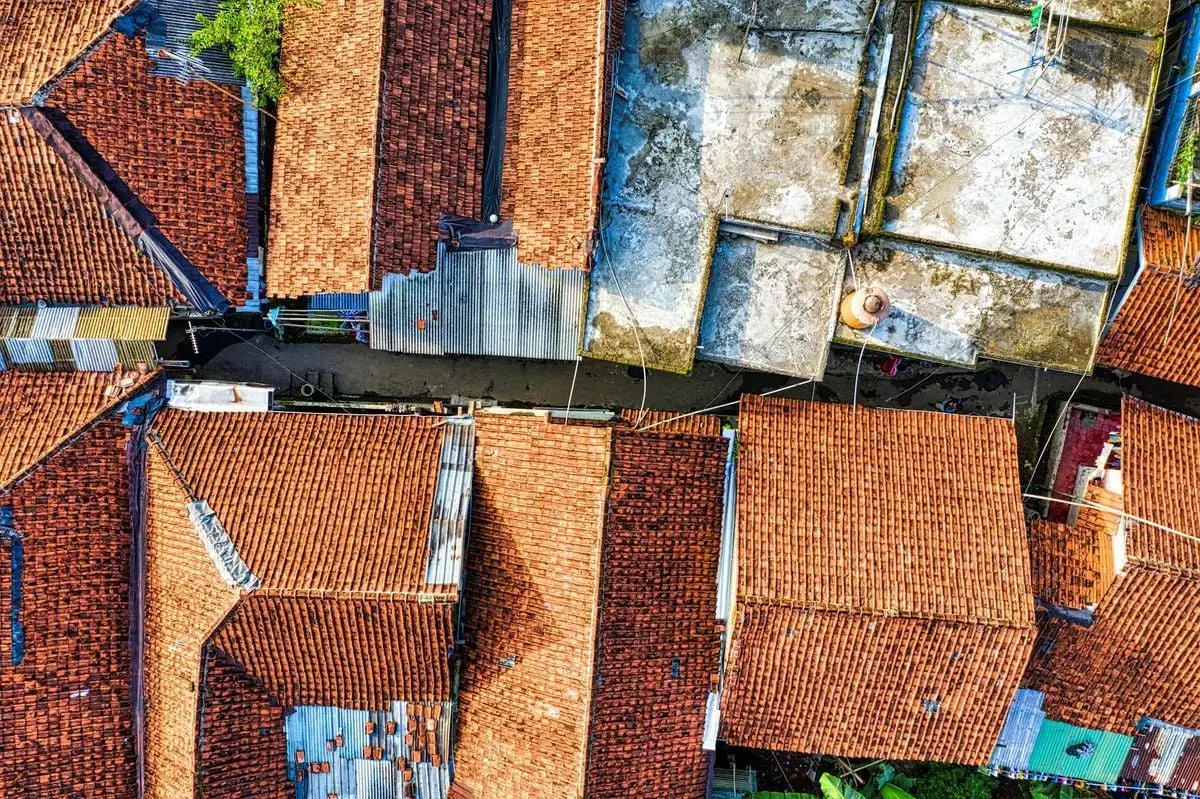 Aerial shot of traditional red-tiled roofs in a densely packed neighborhood in West Java, Indonesia.