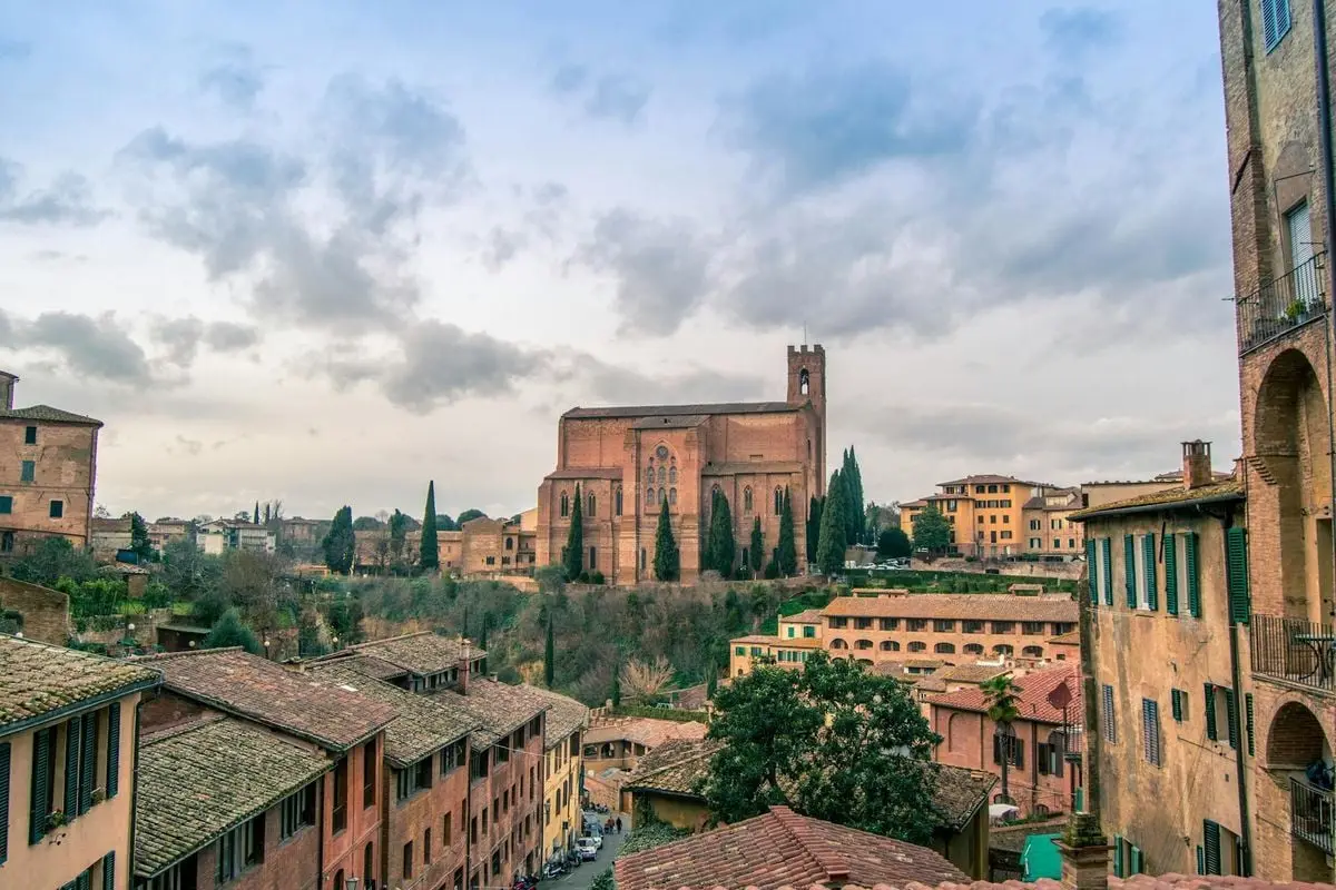 Explore the historic Gothic architecture of the Basilica of San Domenico in Siena, Italy under dynamic skies.