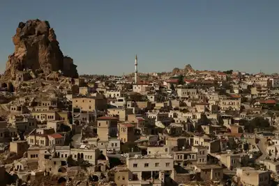 Panoramic view of a historic town in Cappadocia, Türkiye, featuring unique rocky landscapes and traditional architecture.