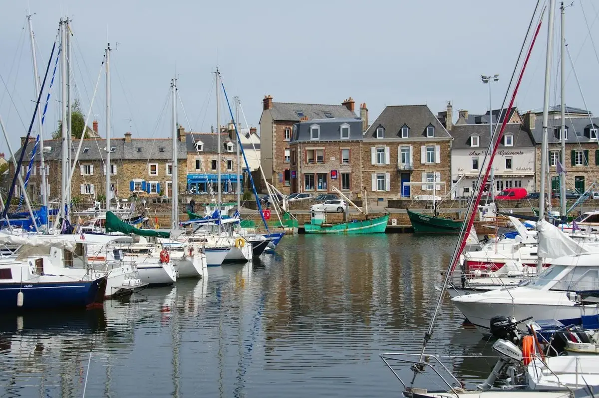 Explore the picturesque marina of Paimpol, France, where sailboats are moored by the colorful historic buildings. Perfect summer scene.