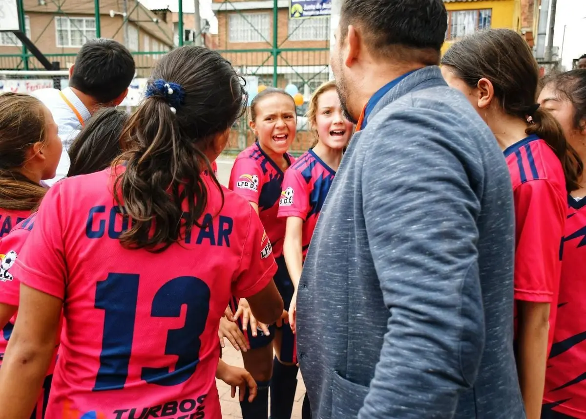 A vibrant moment capturing a youth soccer team in a motivational huddle with their coach, outdoors.