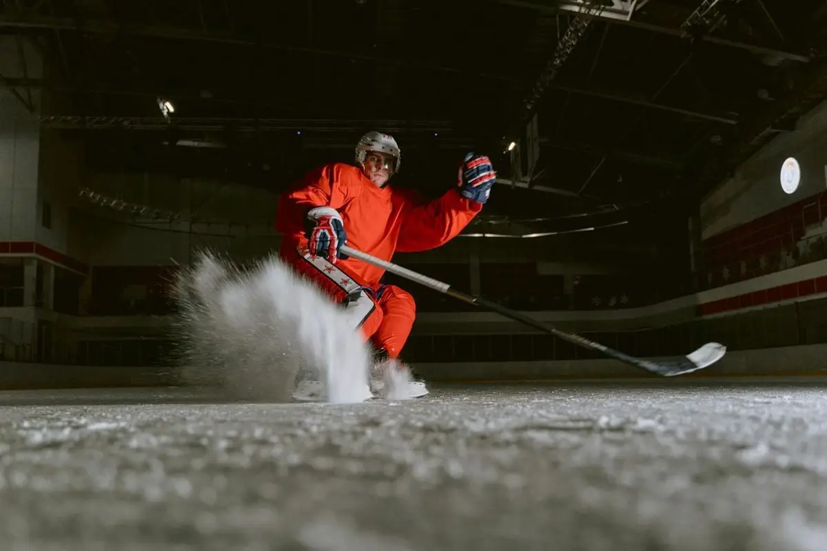 Ice hockey player performing a powerful move on an indoor rink, showcasing skill and speed.