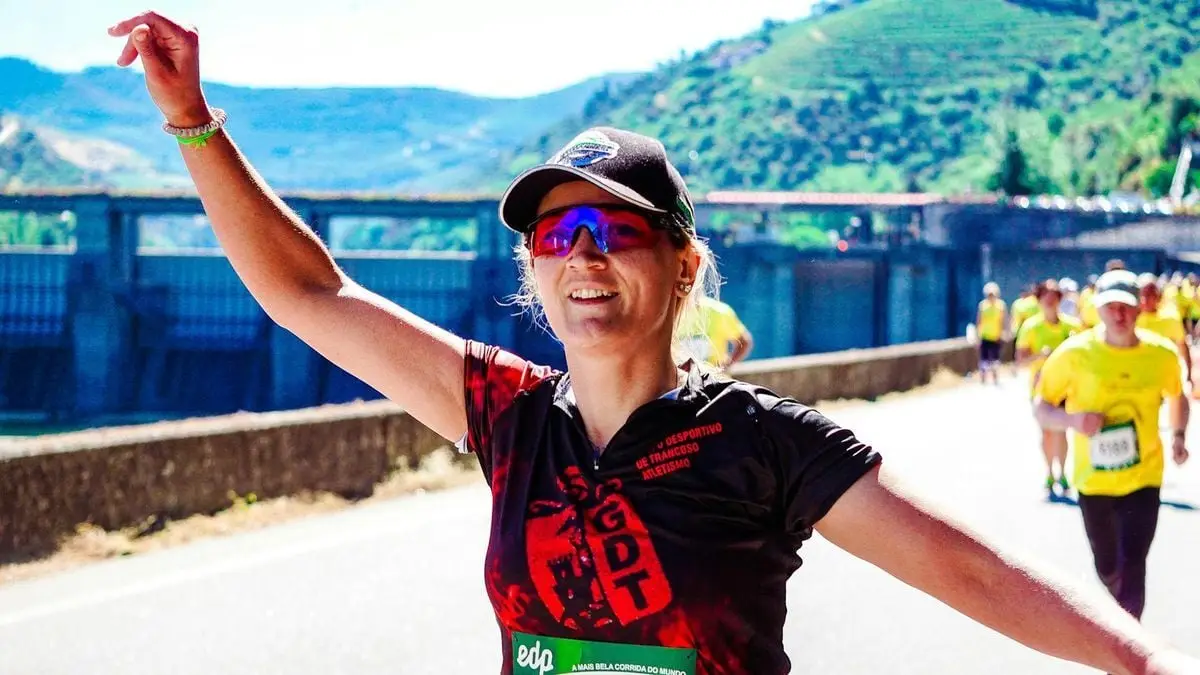 A joyful female runner celebrates during an outdoor marathon on a sunny day.