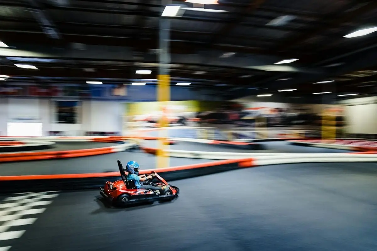 Blurred motion of a go-kart racer speeding on an indoor track during a thrilling race.