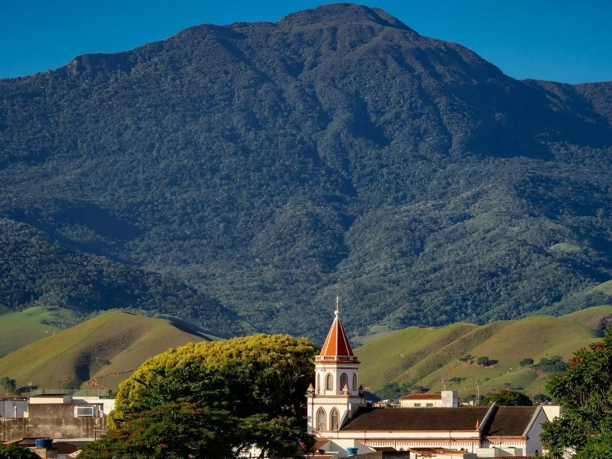 Scenic view of Cruzeiro with lush mountains and iconic church tower against a clear sky.