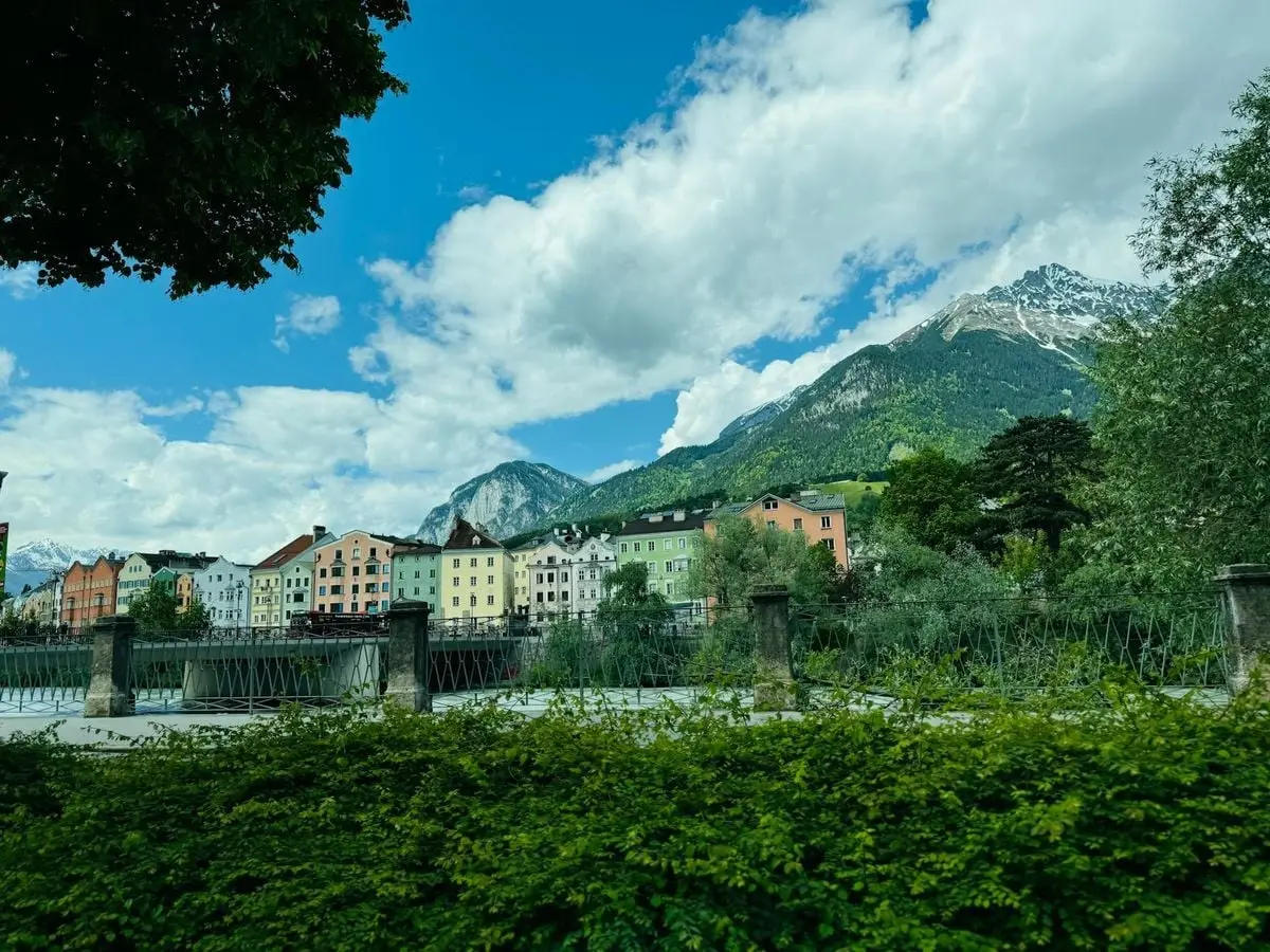 Charming view of colorful townhouses with scenic mountains in Innsbruck, Austria.