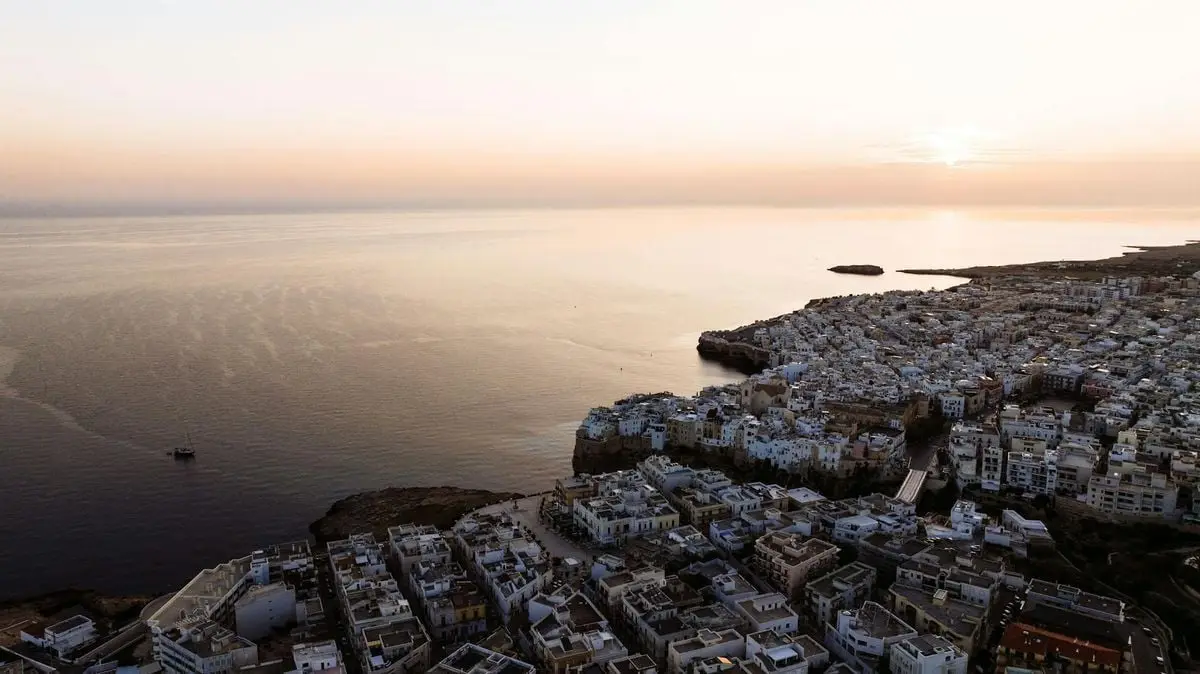 A stunning aerial view of Polignano a Mare and the Adriatic Sea at sunrise. Perfect for travel inspiration.
