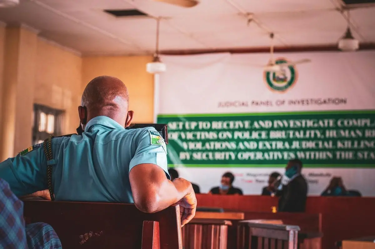 A man in uniform attending a judicial panel meeting indoors.