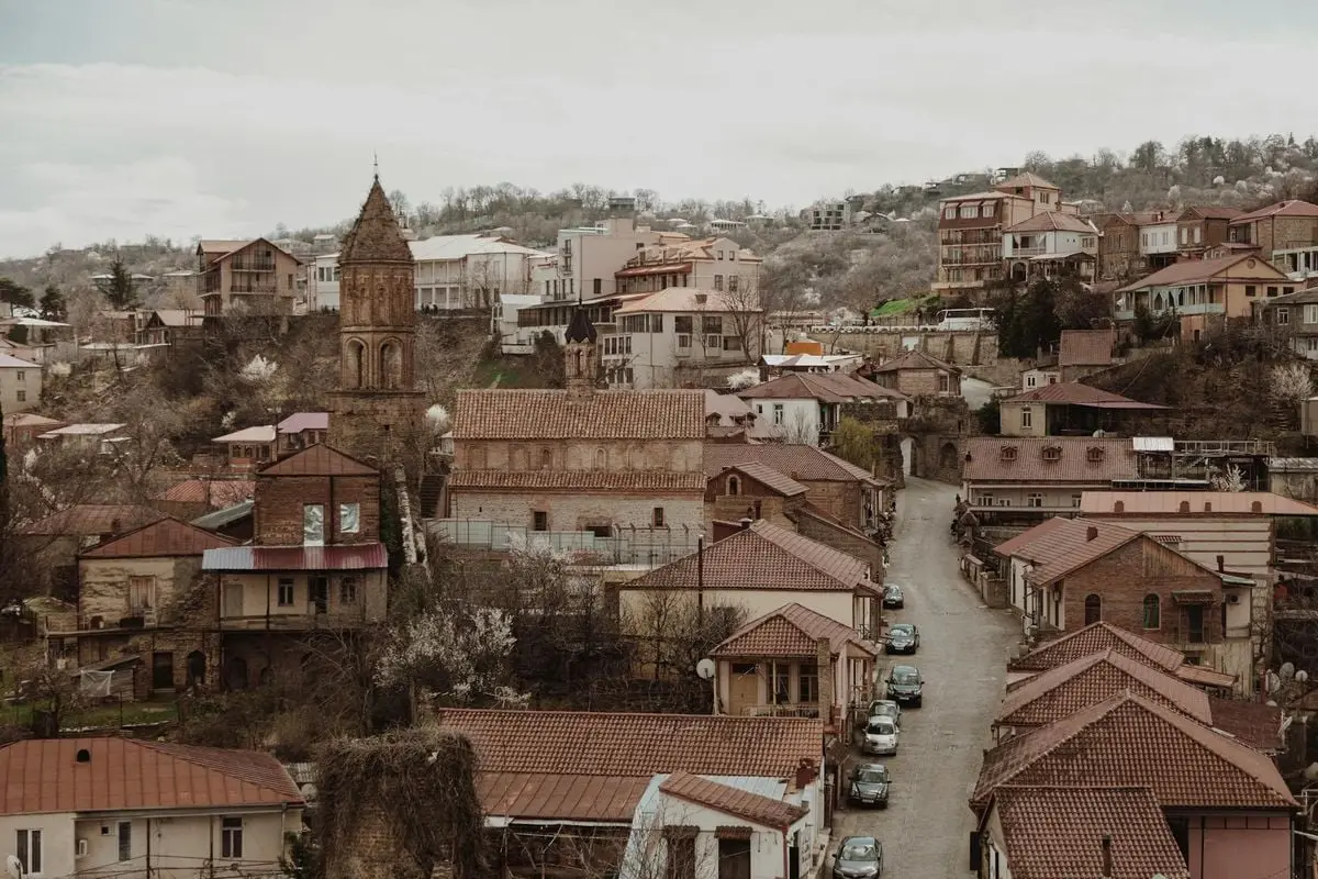 Aerial view of a historical town with brick buildings, narrow streets, and a church tower.