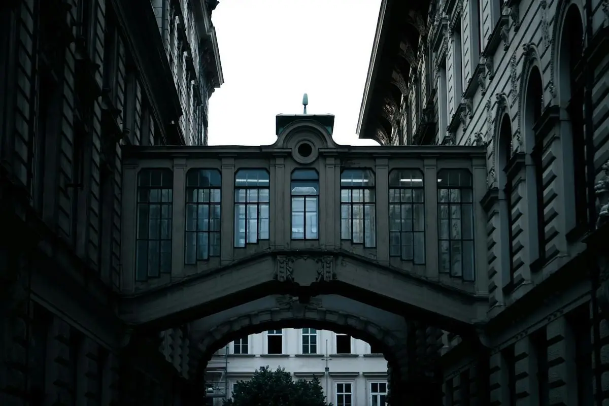A dramatic view of an ornate architectural bridge between buildings in Prague, Czech Republic.