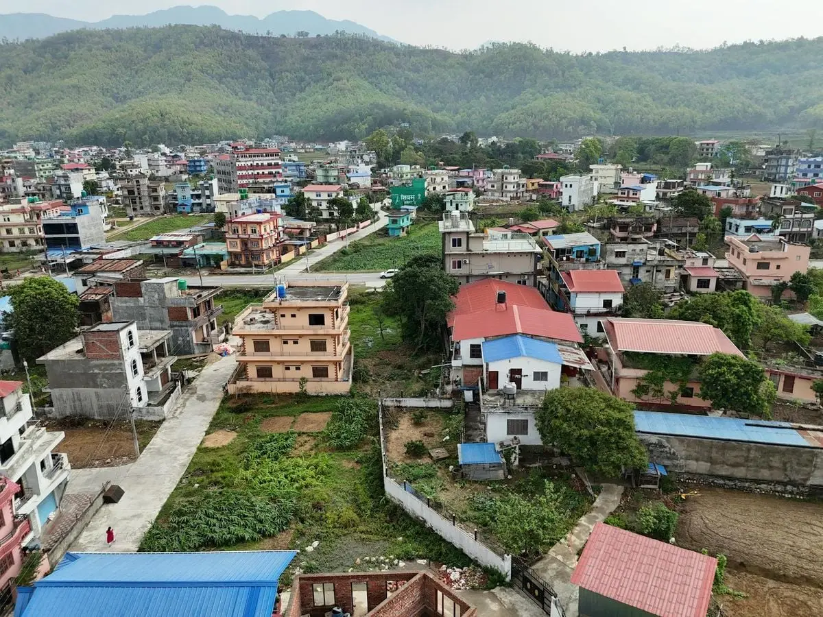 An aerial view of vibrant residential buildings nestled in a lush Nepalese landscape.