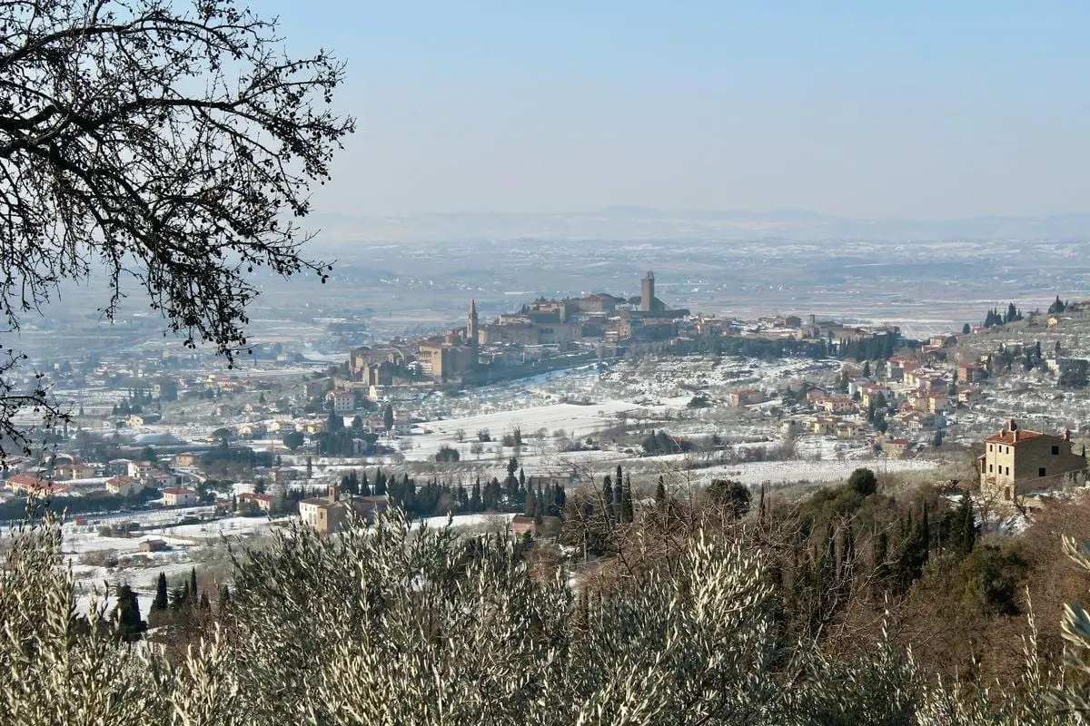 Breathtaking aerial view of Castiglion Fiorentino under a light snowfall, showcasing historic architecture and winter landscape.
