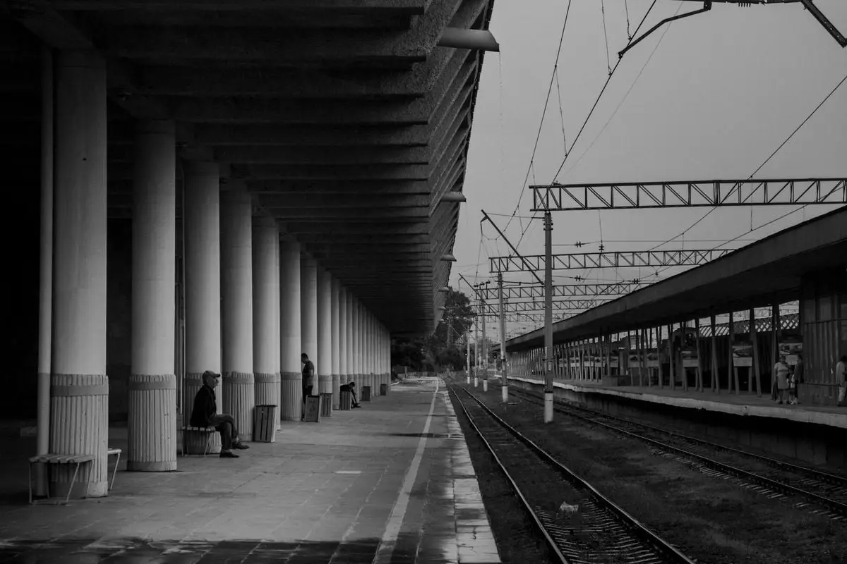 A peaceful and empty train station captured in grayscale showing architectural symmetry.