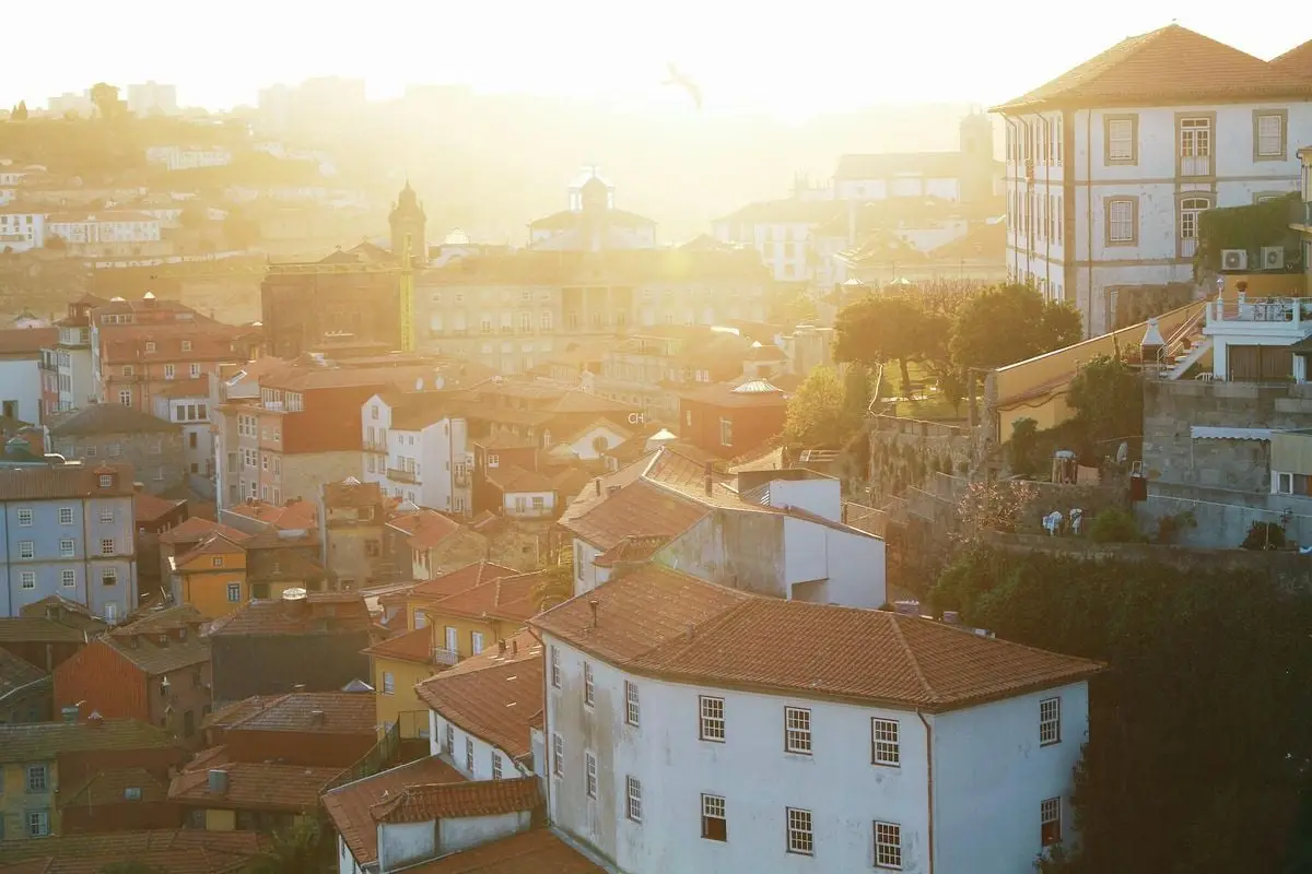 Captivating view of Porto's historic rooftops at sunset, showcasing classic architecture and warm sunlight.