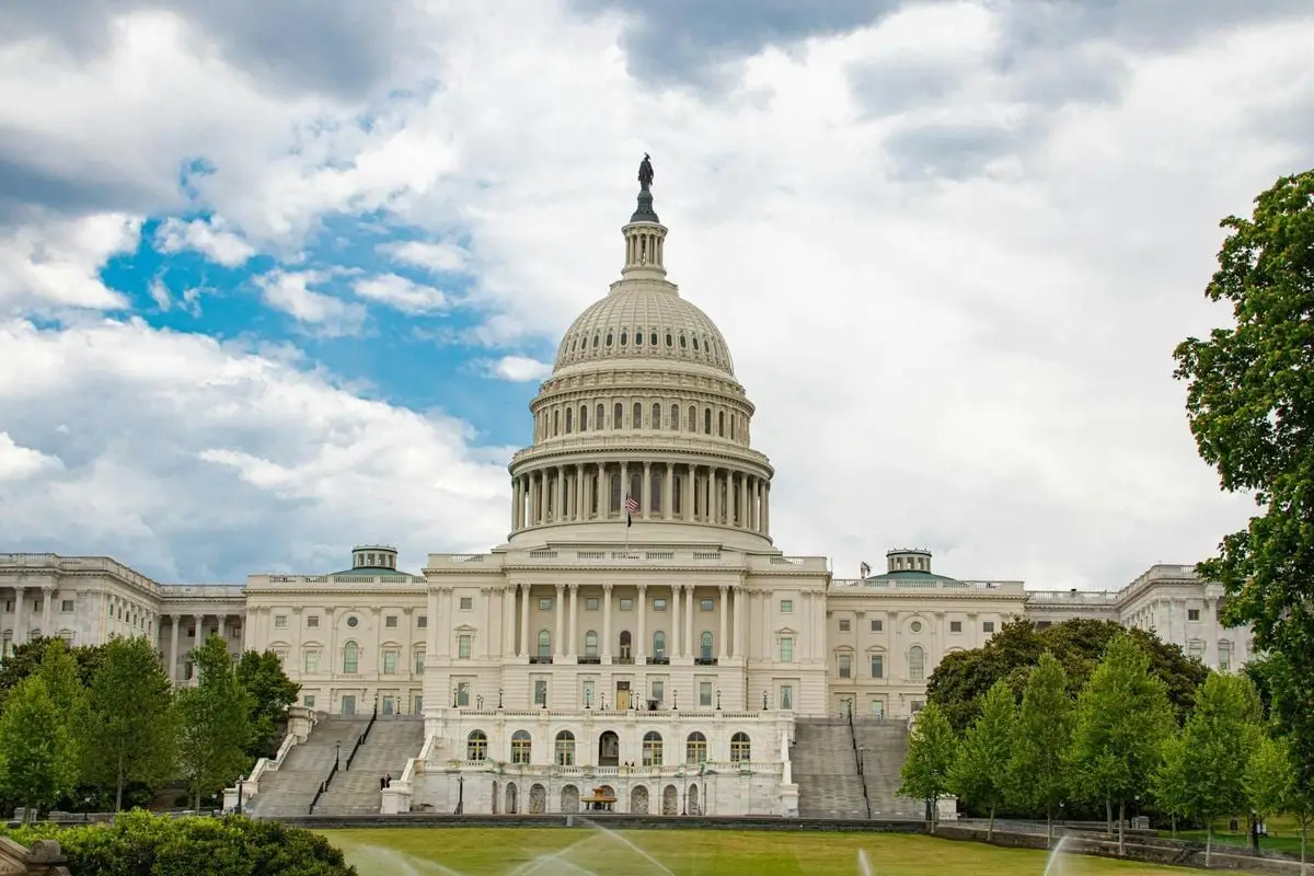 View of United States Capitol with neoclassical architecture against a cloudy sky in Washington D.C.