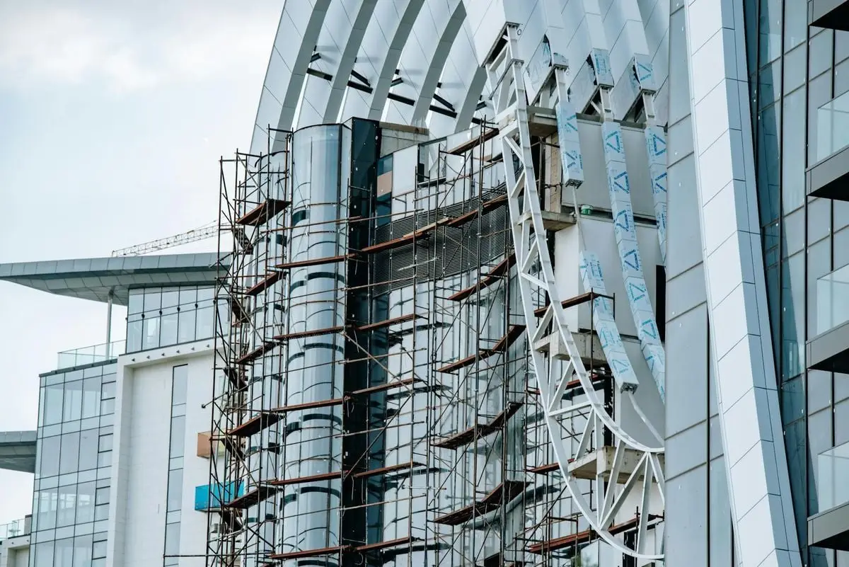 A modern high-rise building under construction, featuring scaffolding and glass panels.