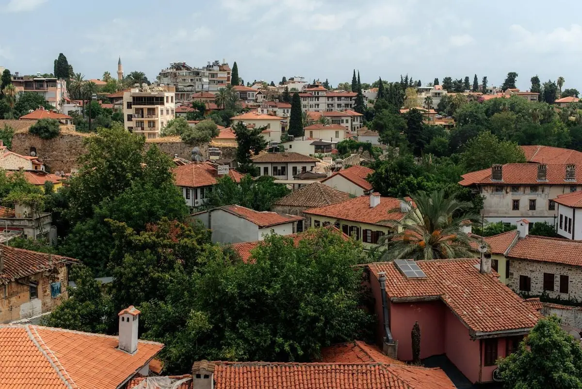 A scenic view of Antalya's old town with red-tiled rooftops and lush greenery.