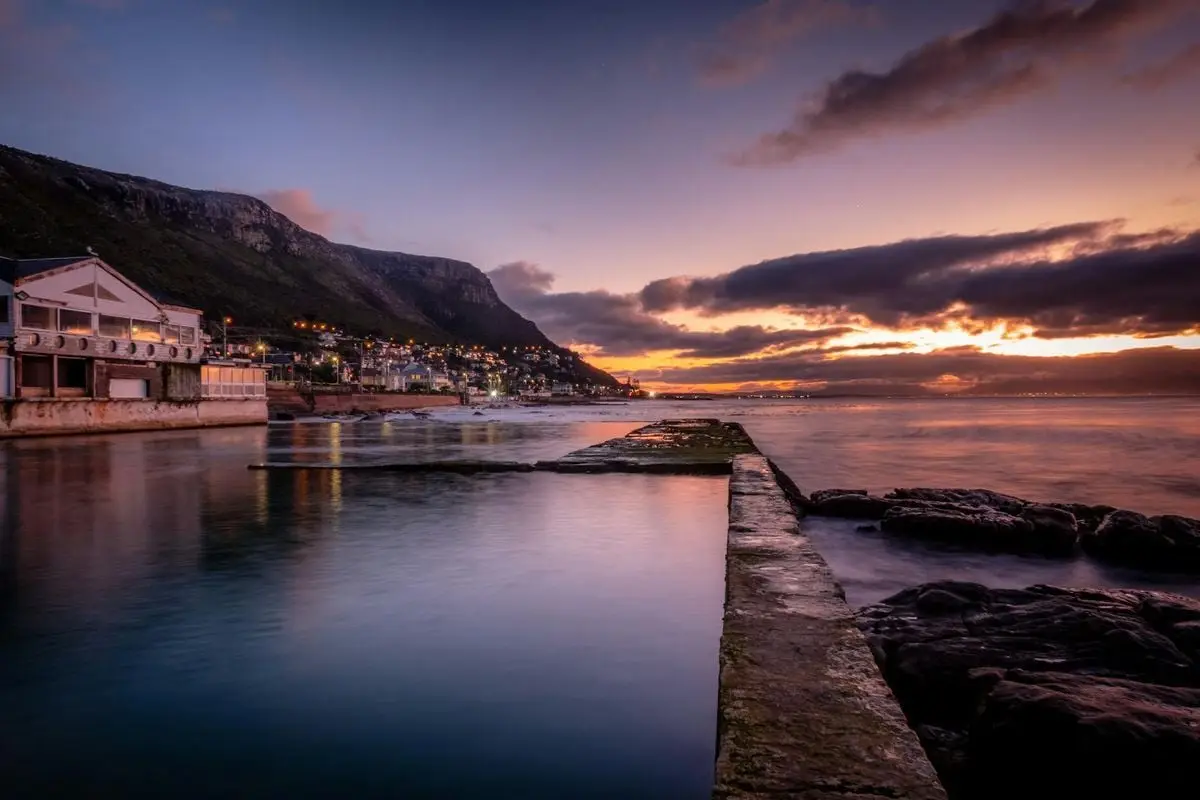 Beautiful sunset over a coastal town with mountains and calm sea.