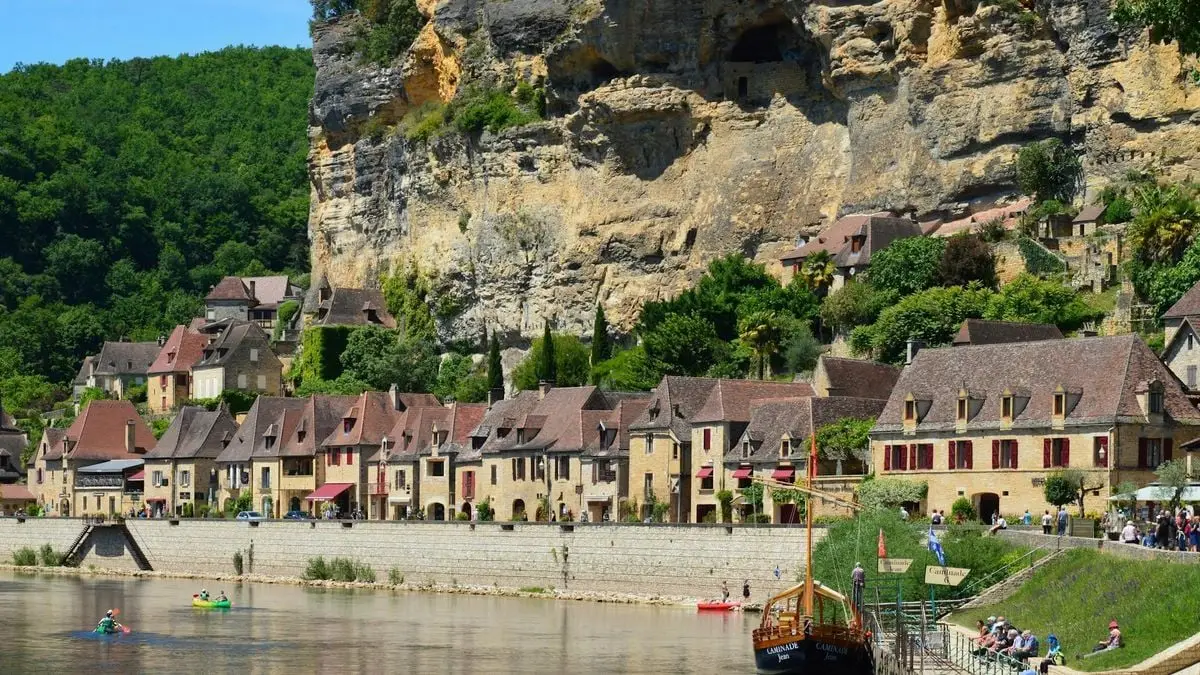 Picturesque village by the river with a stunning rock formation background and charming houses.