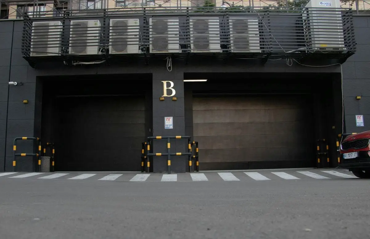Modern garage entrance with air conditioning units above and a zebra crossing in Kyiv, Ukraine.