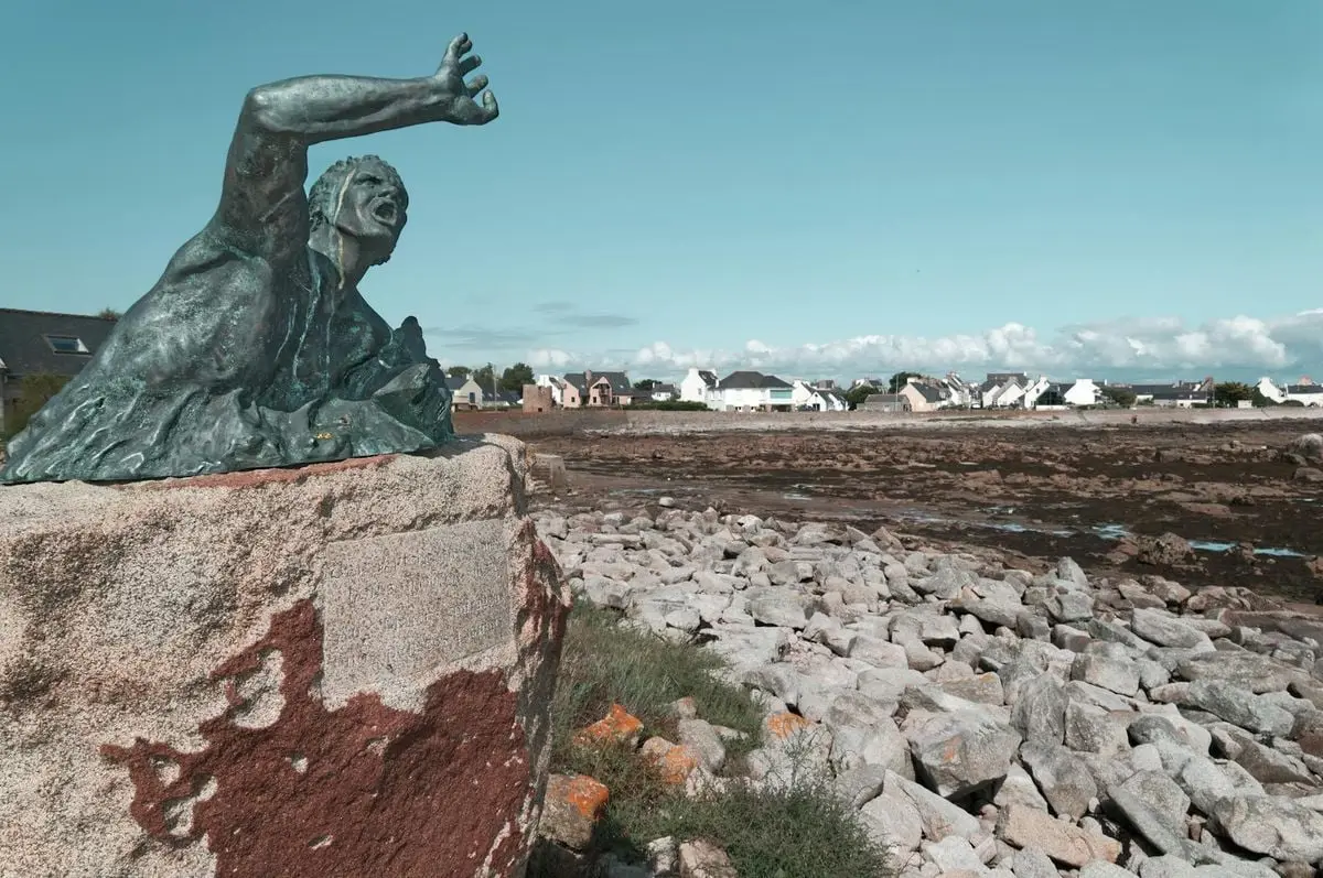 Bronze statue along the rocky seaside in Penmarc'h, Bretagne, France, showcasing cultural heritage and scenic coastal views.