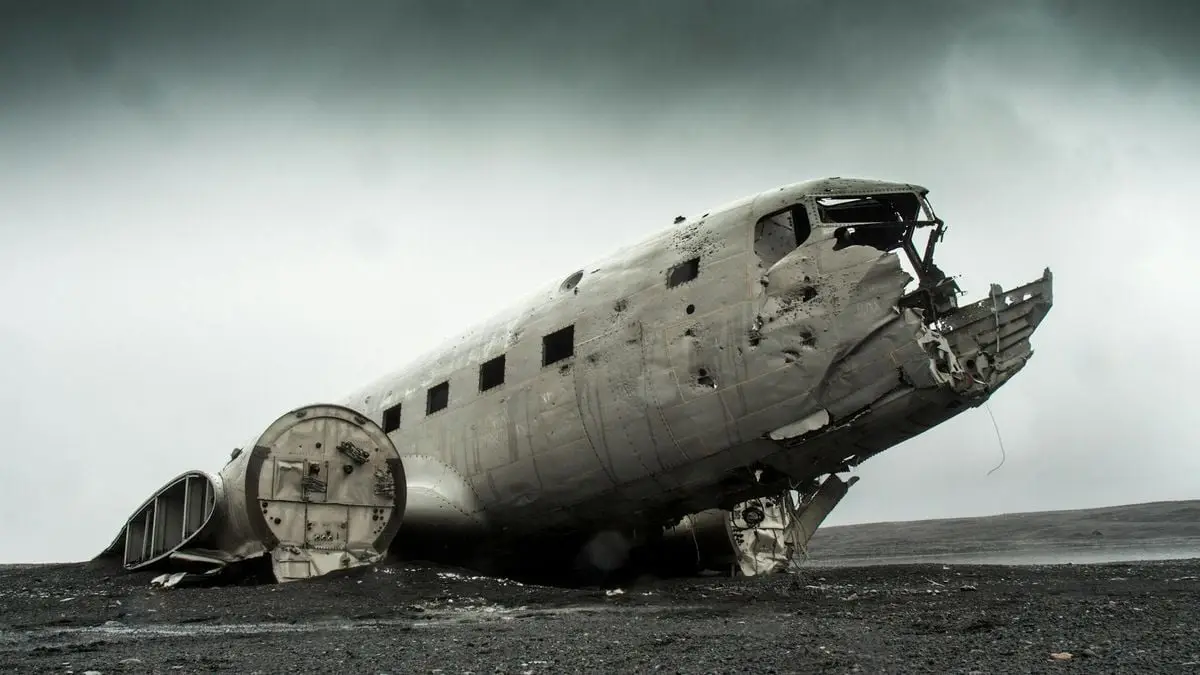 A dramatic photo of a derelict plane wreck on a remote, deserted landscape.