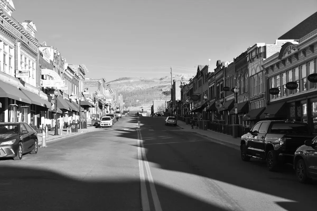 Black and white photo of a historic main street with vintage buildings and cars.