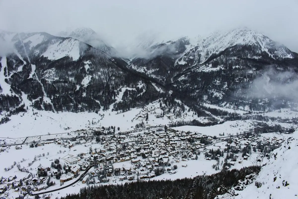 Aerial view of a snowy mountain town nestled in a picturesque valley during winter.