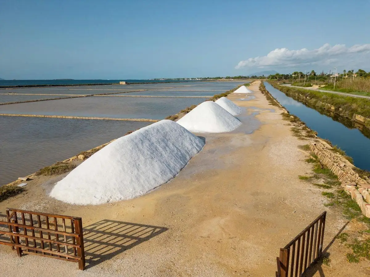 A scenic view of salt piles at Marsala salterns, Italy, captured under a clear sky.