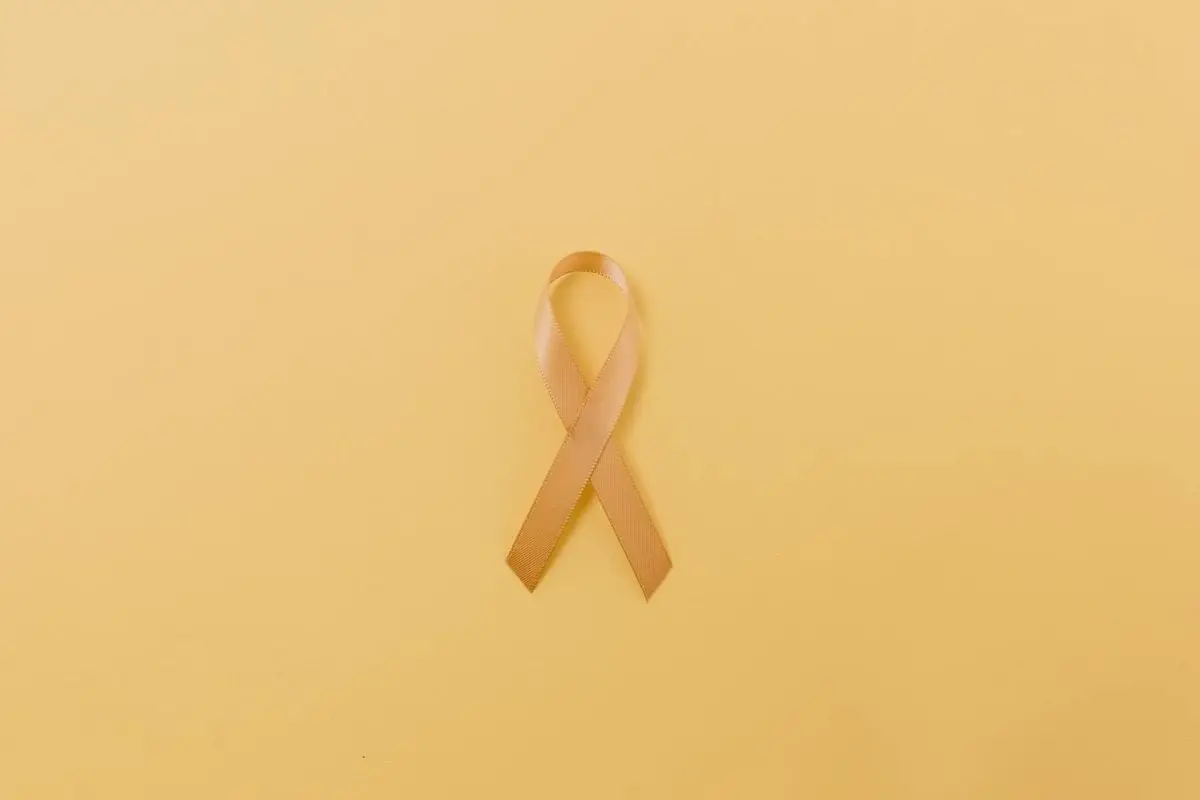 Gold ribbon symbol on a yellow background representing childhood cancer awareness.