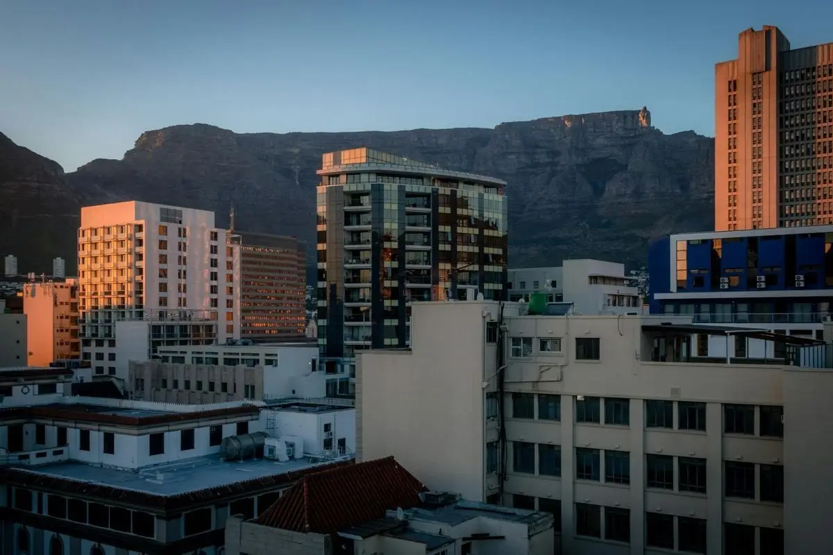 Panoramic view of Cape Town's skyline with Table Mountain at sunset, highlighting urban architecture.