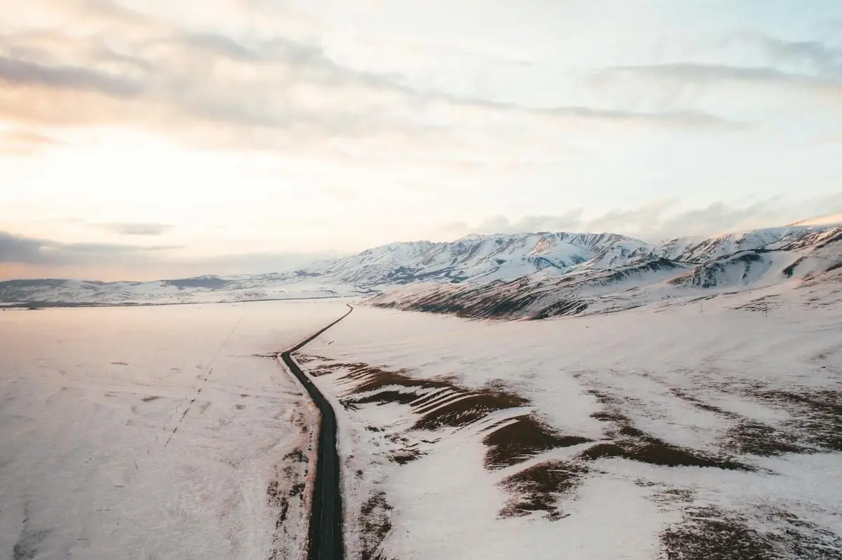 Aerial view of a snow-covered road winding through the Altai Mountains during winter.