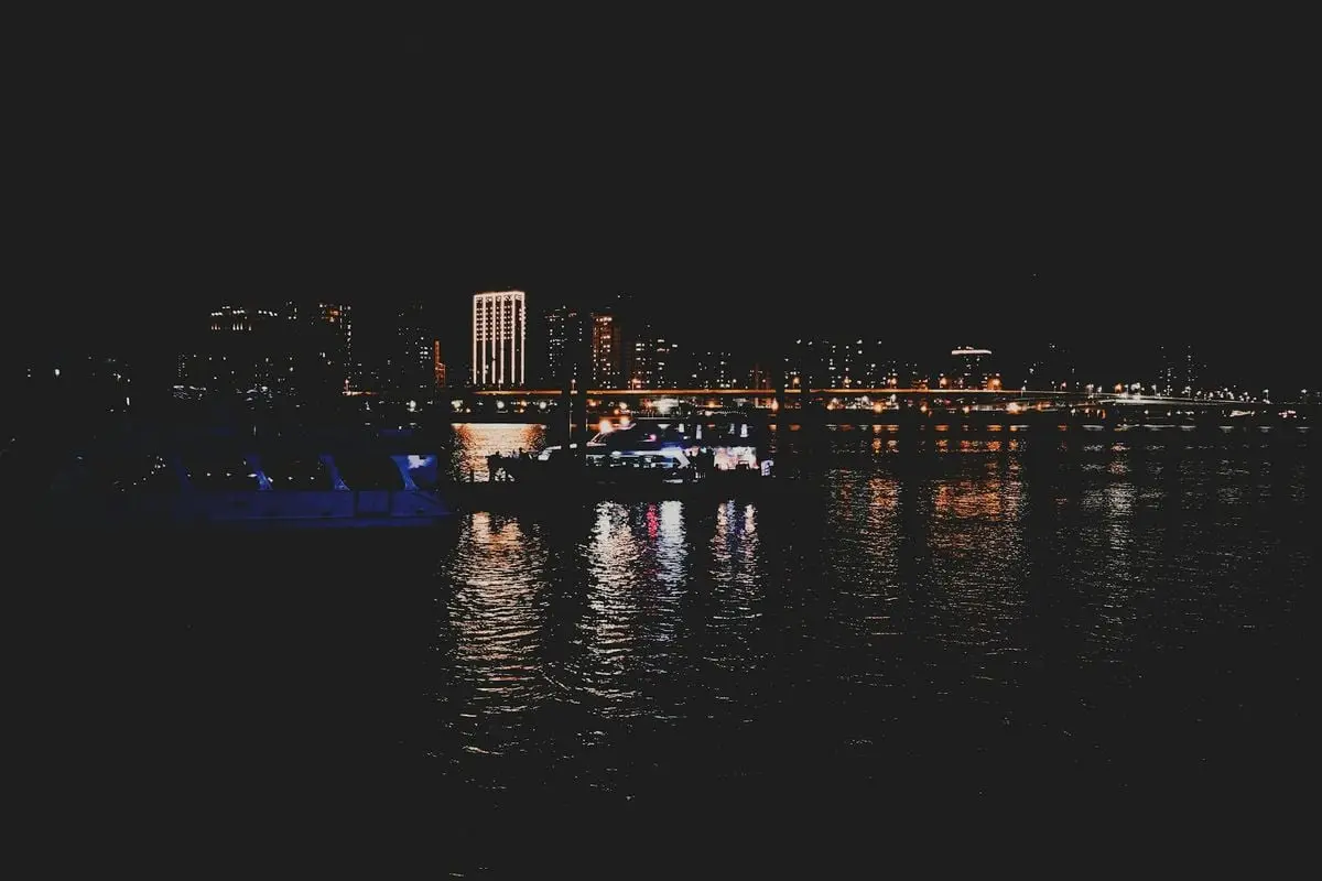 Captivating night view of a cityscape with illuminated buildings and reflections on water.