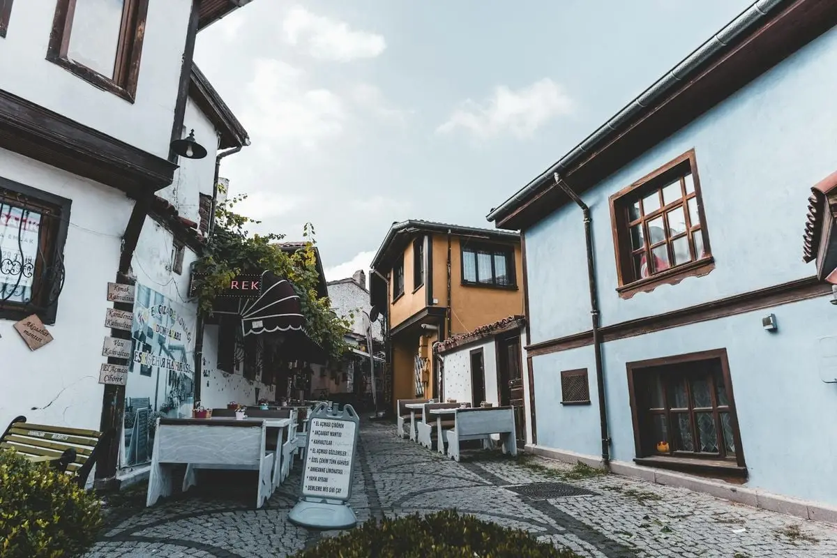 Charming street with cobblestone path and traditional houses under blue sky in historic town.
