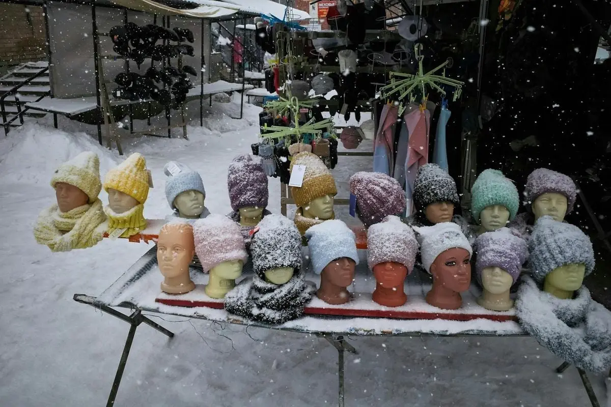 Snow-covered knit hats displayed in a winter street market stall.