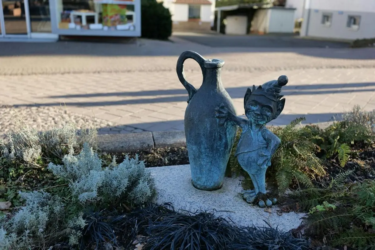 Gnome statue with a large jug in a garden setting in Bad Wildungen, Hessen, Germany.