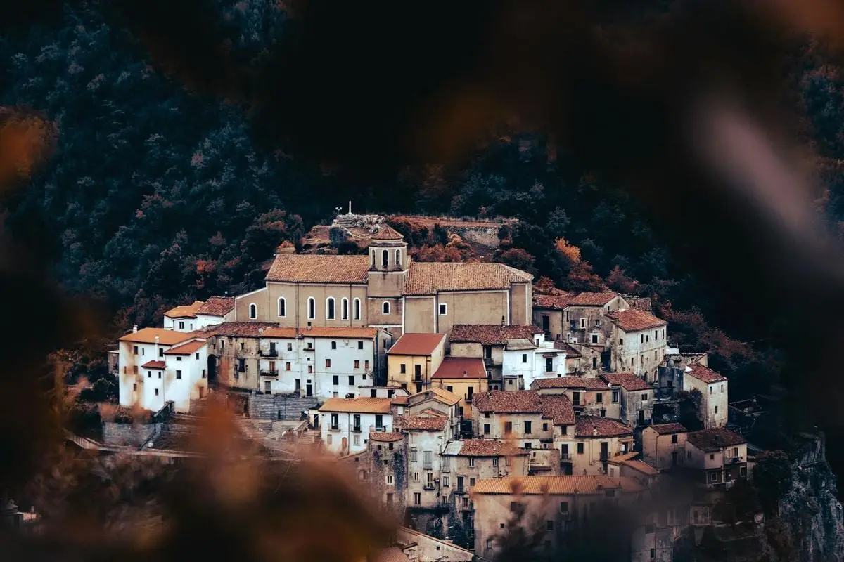Picturesque view of a historic town surrounded by lush mountains in summer.