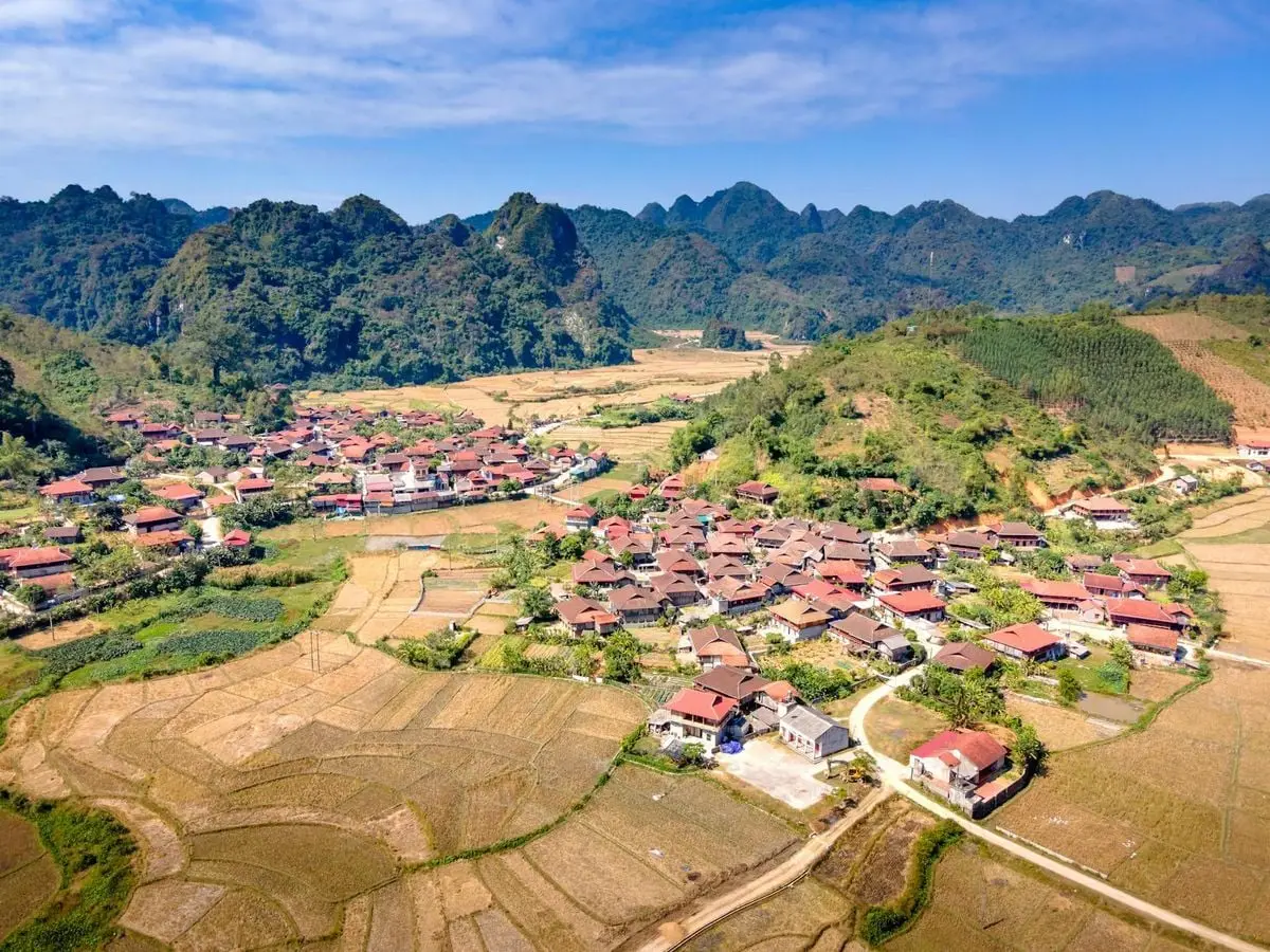 Explore the beauty of a picturesque rural village surrounded by fields and hills in a serene landscape.