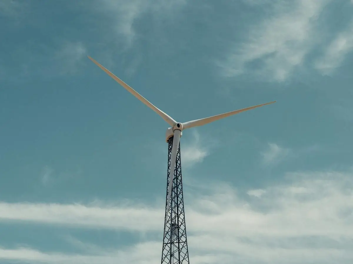 A towering wind turbine stands tall, harnessing wind energy under a clear blue sky.