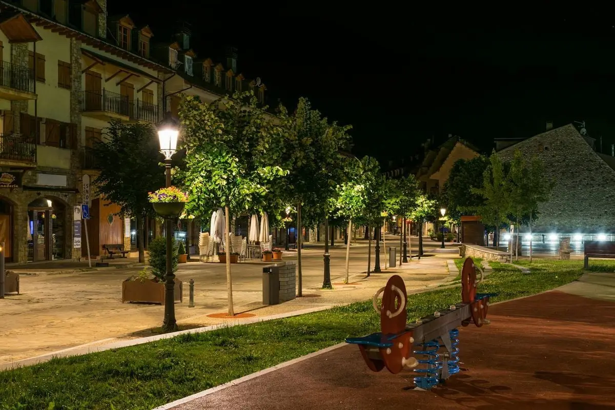 Beautiful night view of a Benasque street with glowing streetlights and lush greenery.