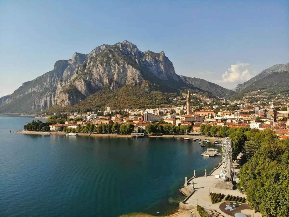 Aerial view of Lecco, Italy with towering mountains and serene waters.