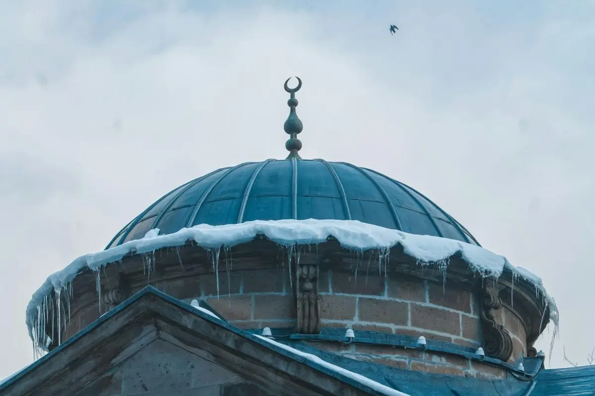 Winter scene of a mosque dome covered in snow and icicles in Kayseri, Türkiye.