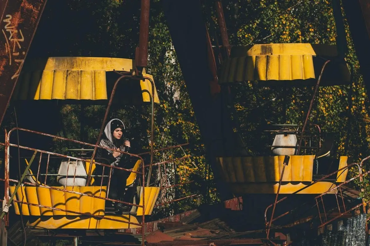 Eerie scene of an abandoned ferris wheel in Chernobyl featuring a lone woman.