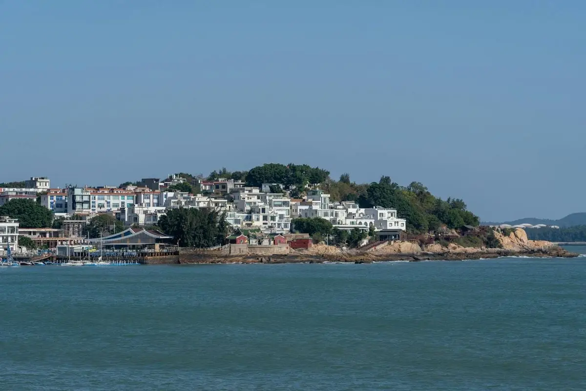 A picturesque coastal townscape with white buildings against the sea and clear blue sky.