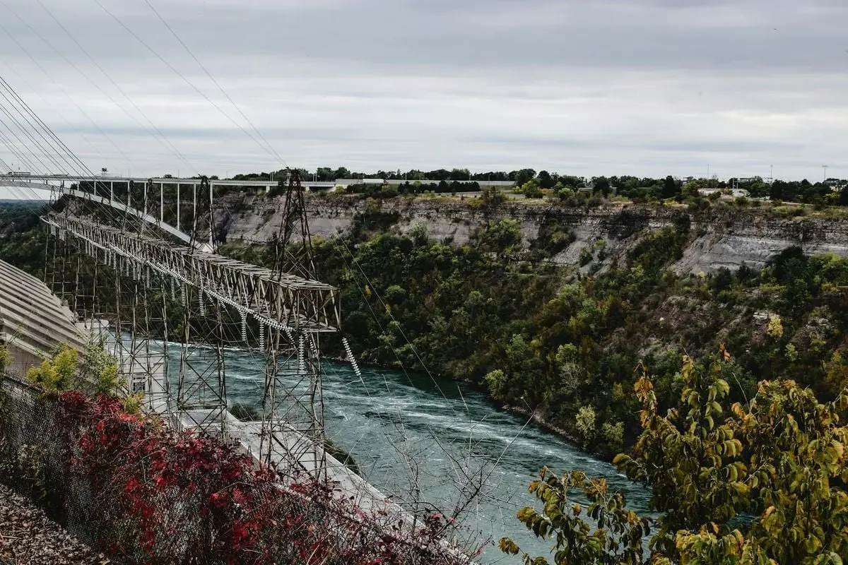 Aerial view of the Niagara Falls river with power lines in autumn, showcasing renewable energy sources.