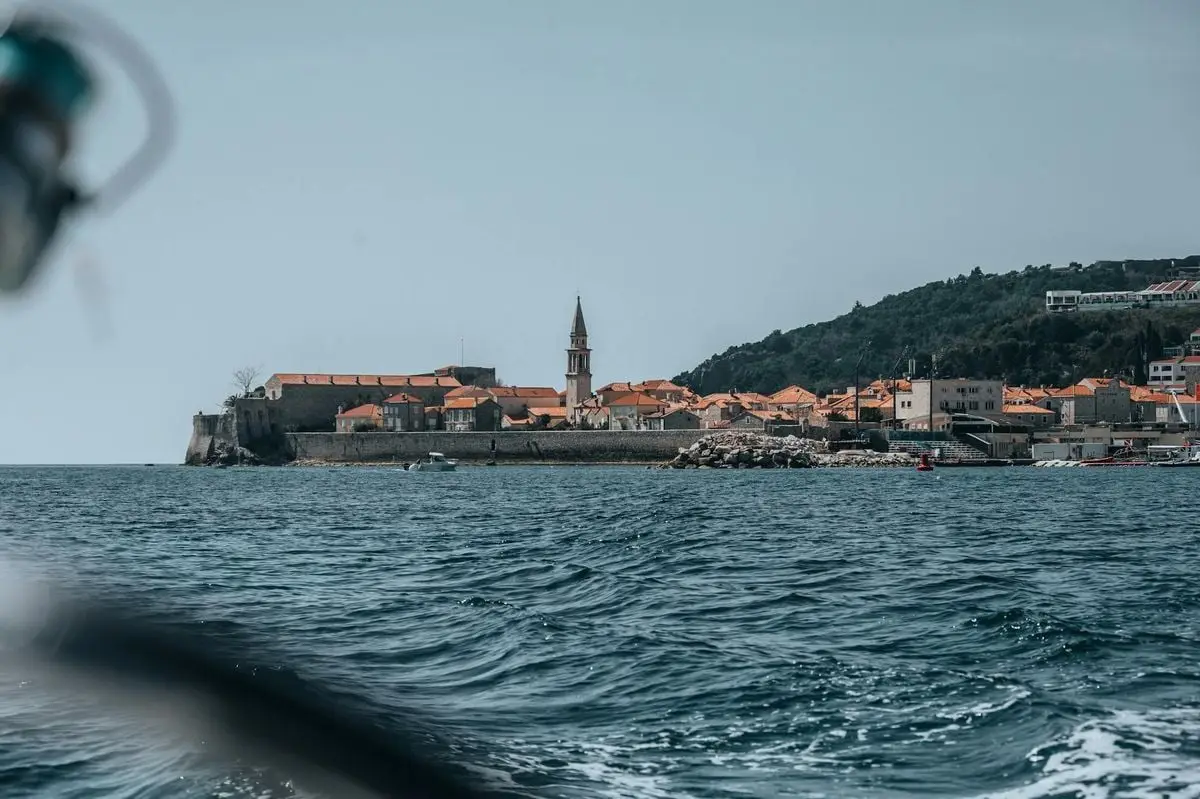 Stunning coastal shot of Budva's old town with its iconic red roofs and church against the Adriatic Sea.