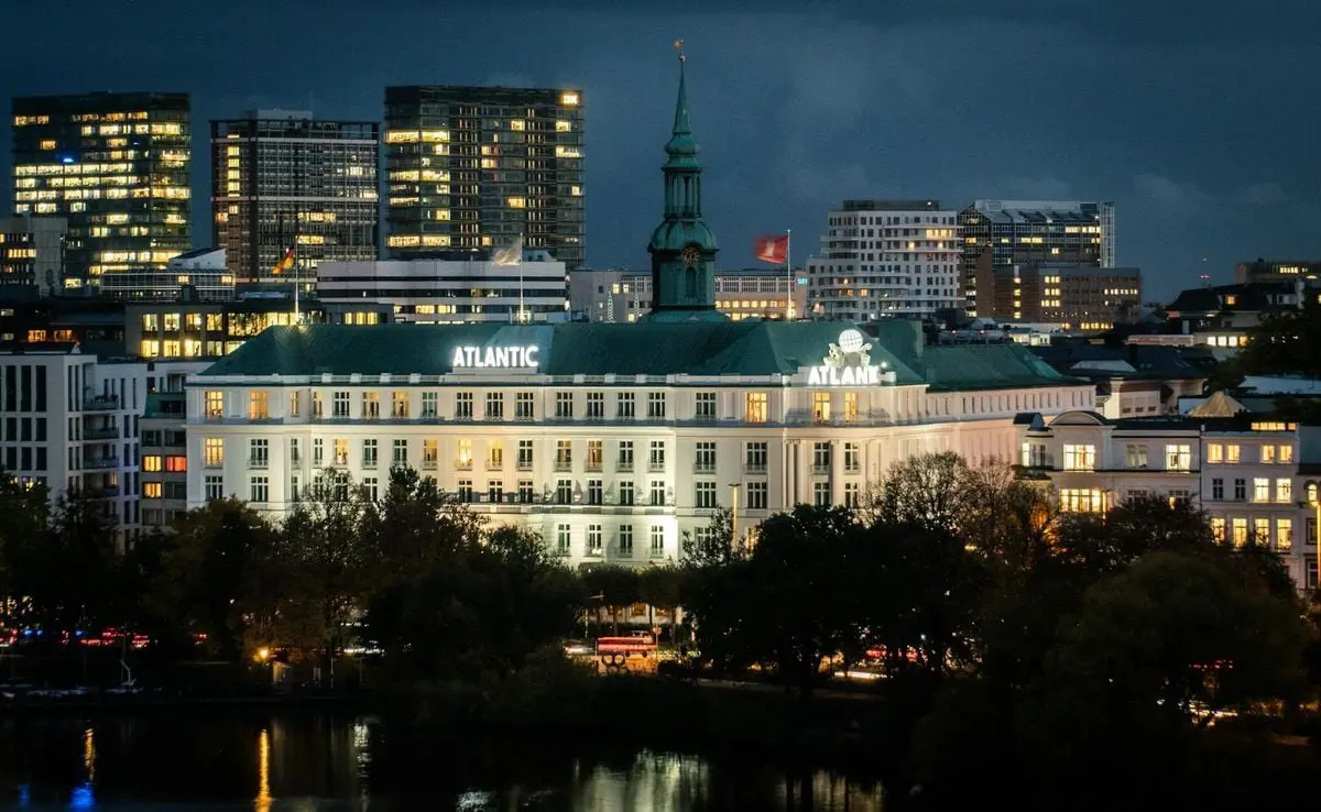 Stunning view of the illuminated Hotel Atlantic in Hamburg reflecting city lights at night.