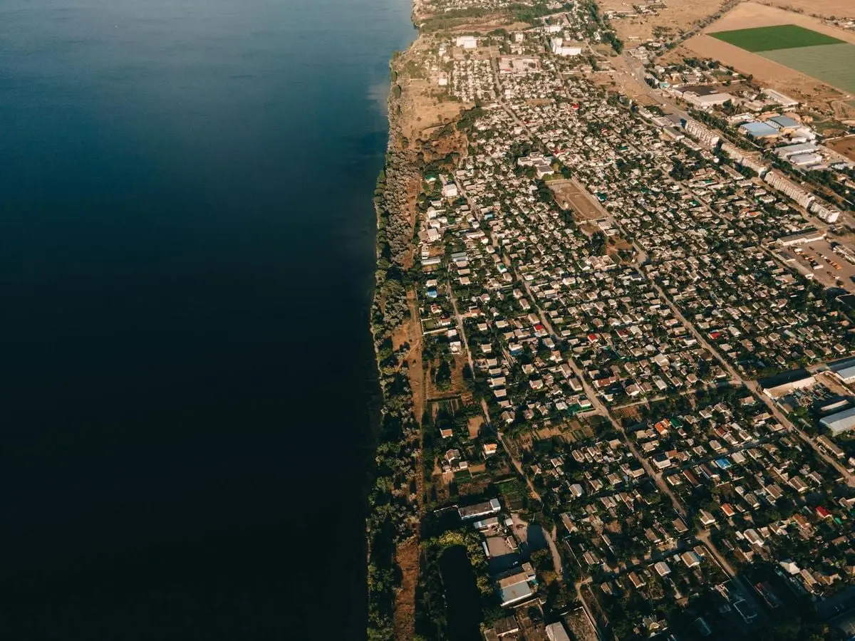 Aerial view of a coastal town next to the ocean, showcasing urban architecture and nature.