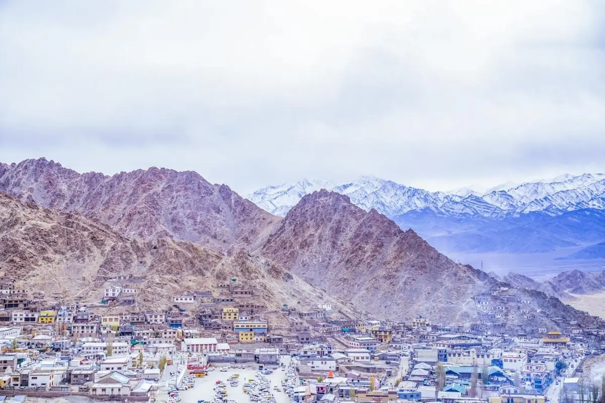 Scenic aerial view of Leh town surrounded by rugged Himalayas and snowcapped peaks in winter.